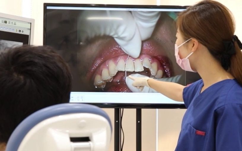 歯周病治療について説明する歯科衛生士
